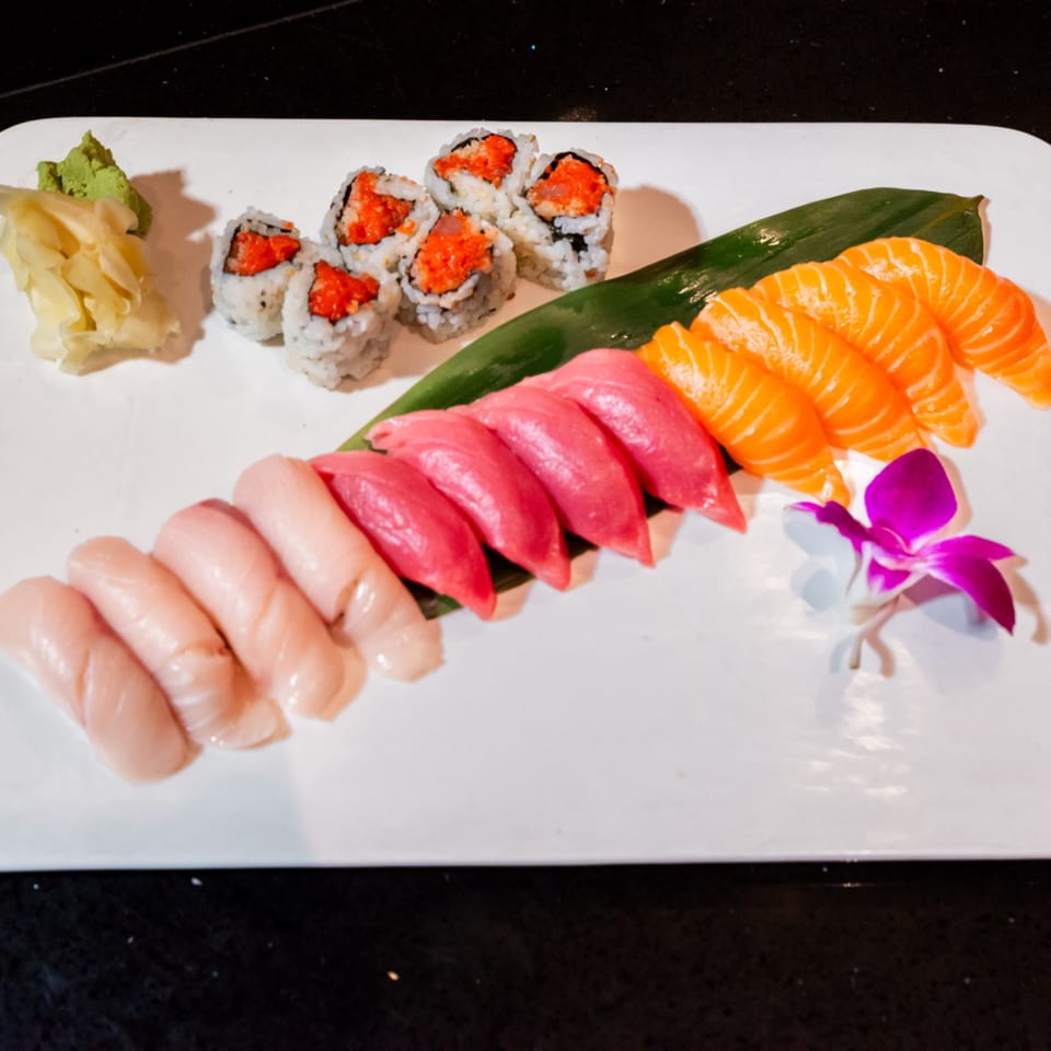 A white platter of Wasabi Japanese SteakHouse sushi, including tuna, salmon, and white fish nigiri, and spicy tuna rolls.