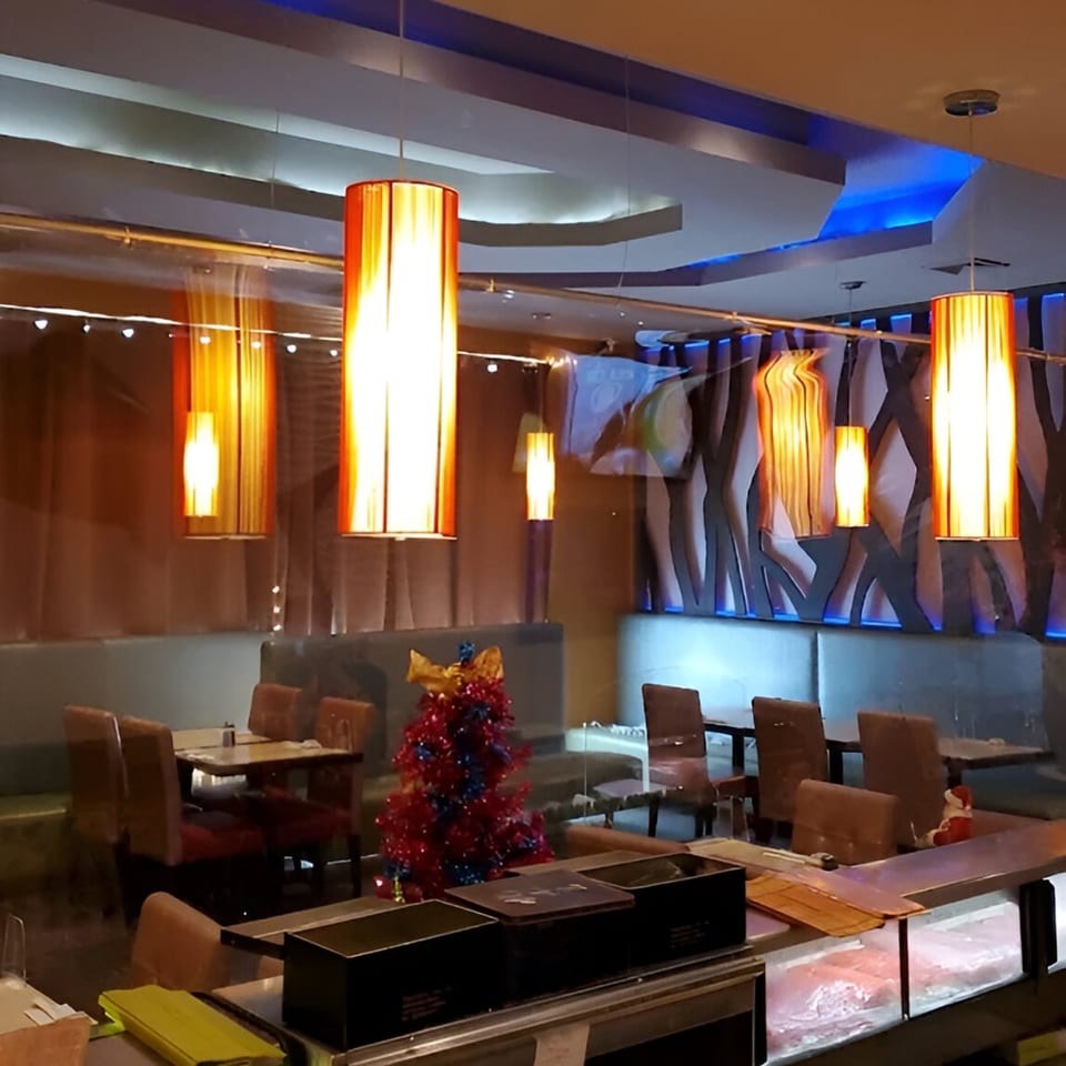Interior of Wasabi Japanese SteakHouse with orange pendant lights, blue ceiling accents, and a small Christmas tree.