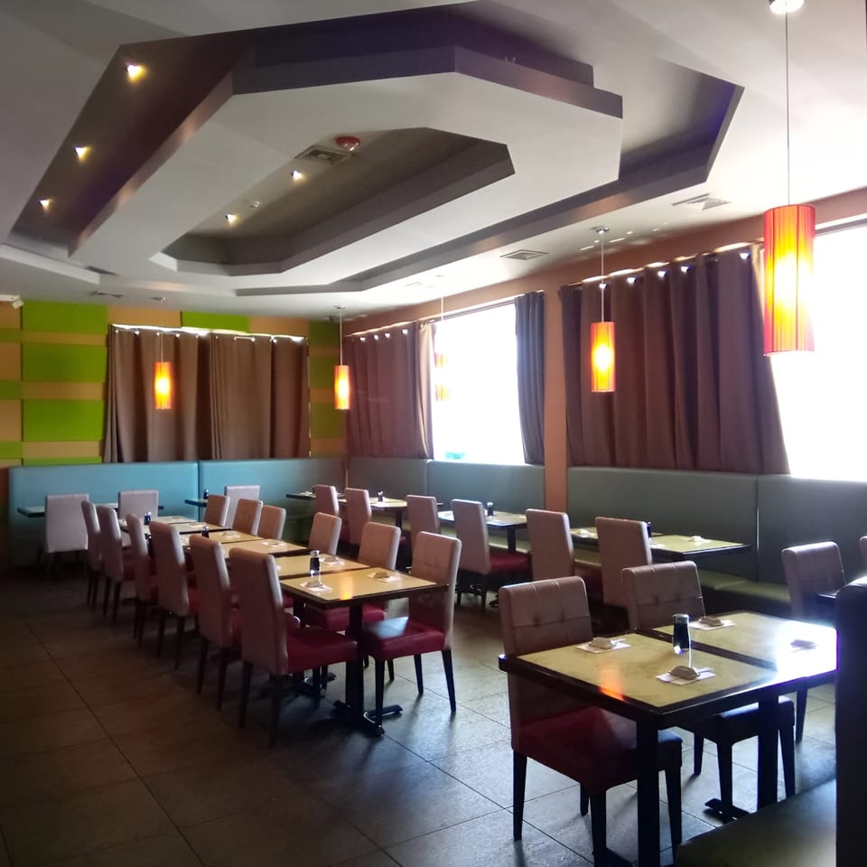 Interior of Wasabi Japanese SteakHouse with empty tables, red chairs, and warm lighting.